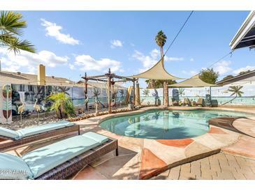 Outdoor oasis with a freeform pool, lush landscaping, and lounge chairs at 2505 E Hampton Ave, Mesa, AZ 85204