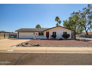 Charming single-story home featuring a two-car garage, red front door, and a well-manicured front yard at 2801 E Sylvia St, Phoenix, AZ 85032