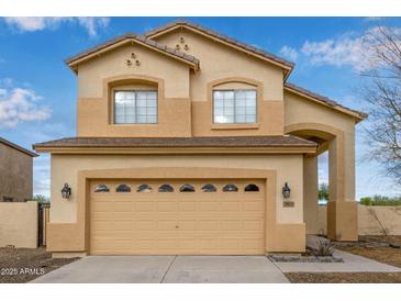 Two-story tan home featuring an attached garage, arched entrance, and well-maintained landscaping at 2834 N Paisley Ln, Casa Grande, AZ 85122