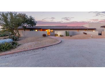 Warm desert home featuring desert landscaping, private courtyard, and red tiled roof at dusk at 36801 N Long Rifle Rd, Carefree, AZ 85377