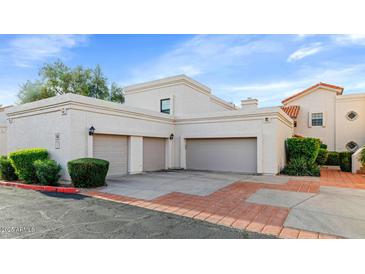 Beige stucco house with three-car garage and brick-lined driveway for a beautiful curb appeal at 7800 E Lincoln Dr # 1104, Scottsdale, AZ 85250