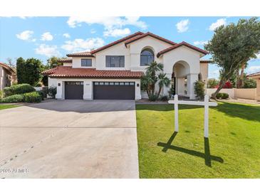 Two-story home showcasing a tile roof, three-car garage, arched entryway, and verdant lawn with a real estate sign at 9159 N 108Th Pl, Scottsdale, AZ 85259