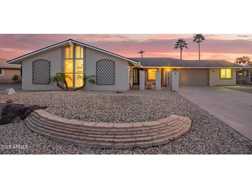 Charming single-story home with a low-maintenance gravel yard, desert landscaping, and palm trees at 11005 W Crestbrook Dr, Sun City, AZ 85351