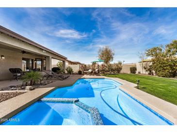 Inviting backyard features a sparkling pool, lush lawn, patio, and mature desert landscaping at 13238 W Market St, Surprise, AZ 85374