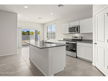 Modern kitchen with island, stainless appliances, granite countertops, and a sliding glass door at 1372 W Hess Ave, Coolidge, AZ 85128