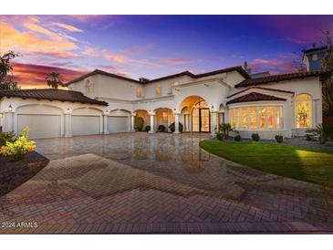 Elegant home featuring a three-car garage, stunning arches, manicured lawn, and a brick paved driveway at 1523 E Treasure Cove Dr, Gilbert, AZ 85234