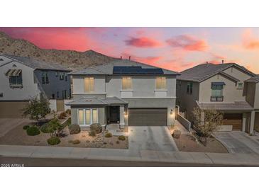 Charming two-story home featuring solar panels and a meticulously landscaped front yard against a mountain backdrop at 21186 W Hillcrest Blvd, Buckeye, AZ 85396