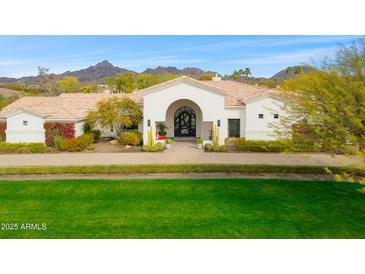 Stunning single-story home with a beautiful arched entryway, lush landscaping, and mountain views at 3246 E San Miguel Pl, Paradise Valley, AZ 85253