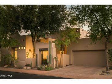 Charming exterior of a single-story home featuring mature trees, desert landscaping, and a private two-car garage at 6711 E Camelback Rd # 81, Scottsdale, AZ 85251