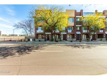 A street view of a modern brownstone featuring landscaped sidewalks and vibrant greenery at 6745 N 93Rd Ave # 1166, Glendale, AZ 85305