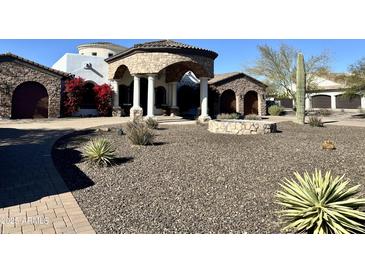 Stunning home exterior with stone accents, desert landscaping, and a circular driveway creates an inviting curb appeal at 8214 E Kael St, Mesa, AZ 85207