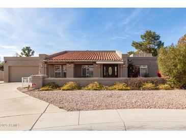 Charming single-story home featuring a red tile roof, low rock landscaping, and front porch at 8544 E San Lorenzo Dr, Scottsdale, AZ 85258