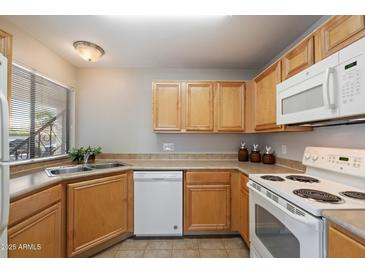 Kitchen with wooden cabinets, white appliances and a double stainless steel sink at 10115 E Mountain View Rd # 1119, Scottsdale, AZ 85258
