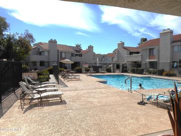 Inviting community pool with lounge chairs, clear blue water, and surrounding residential buildings under a sunny sky at 10115 E Mountain View Rd # 1119, Scottsdale, AZ 85258