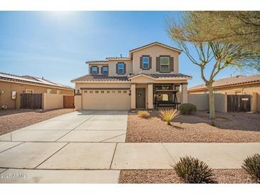 Two-story home featuring a charming front porch swing, a two car garage, and desert landscaping at 16993 W Shiloh Ave, Goodyear, AZ 85338