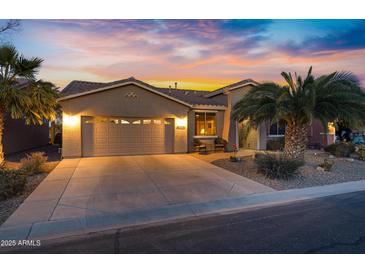 Charming single-story home featuring a two-car garage, desert landscaping and a beautiful sunset sky at 20207 N Riverbank Rd, Maricopa, AZ 85138