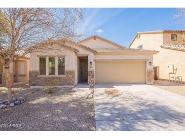 Charming single-story home featuring a two-car garage, desert landscaping, and a stone facade at 38672 N Establo Dr, San Tan Valley, AZ 85140