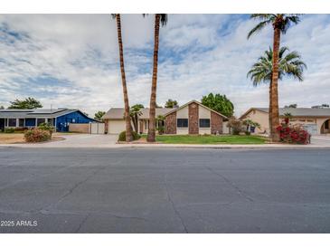 Charming single-story home featuring brick accents, lush landscaping, and mature palm trees at 3938 E Gable Ave, Mesa, AZ 85206