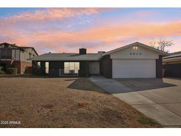 Charming single-story home with a well-manicured lawn and attached two-car garage at 5013 W Orchid Ln, Glendale, AZ 85302