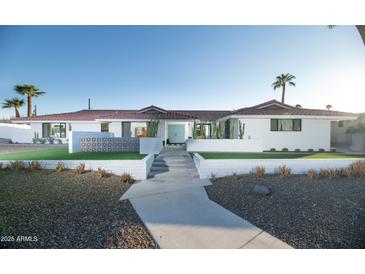 Charming white single-story home featuring a well-manicured landscape, complemented by palm trees and a blue door at 5801 N 22Nd Pl, Phoenix, AZ 85016