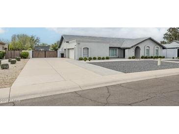 View of home's driveway, landscaping and gray exterior at 11942 N 95Th St, Scottsdale, AZ 85260