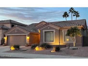 Charming single-story home featuring desert landscaping, a neutral color palette, and well-lit exterior at dusk at 1314 W Windsong Dr, Phoenix, AZ 85045