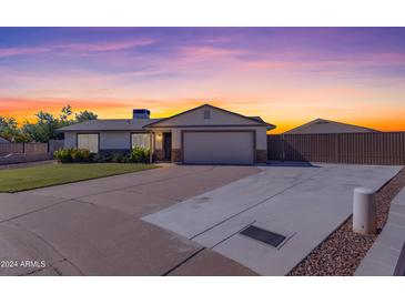 Charming single-story home featuring a spacious driveway, a two-car garage, and a manicured front lawn at sunset at 1840 N Brighton Cir, Mesa, AZ 85207