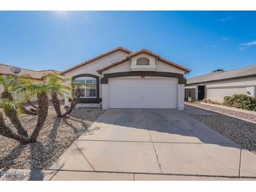 Charming single-story home featuring a two-car garage and desert landscaping with mature palm trees under a clear blue sky at 3043 W Melinda Ln, Phoenix, AZ 85027