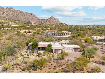 Expansive desert home with a tile roof and attached garage blends seamlessly with the natural landscape and mountain views at 6432 E Old Paint Trl, Carefree, AZ 85377