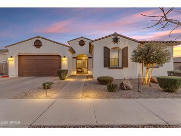Charming single-story home with a two-car garage, desert landscaping, and a welcoming entrance at dusk at 22837 E Silver Creek Ln, Queen Creek, AZ 85142