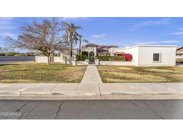 Sprawling home exterior featuring a well-maintained lawn, mature trees, and a stucco wall for added privacy at 4010 E Grandview St, Mesa, AZ 85205