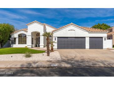 Charming single-story home with a three-car garage, desert landscaping, and a bright, welcoming facade at 5456 E Woodridge Dr, Scottsdale, AZ 85254