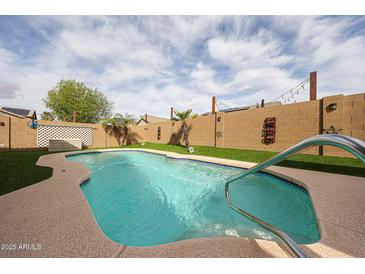 Inviting pool area featuring a sparkling pool, artificial grass and tall privacy walls, perfect for outdoor enjoyment at 12622 W Avalon Dr, Avondale, AZ 85392