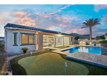 Beautiful backyard with a pool, putting green, and outdoor kitchen, perfect for entertaining guests at 15837 W Bonitos Dr, Goodyear, AZ 85395