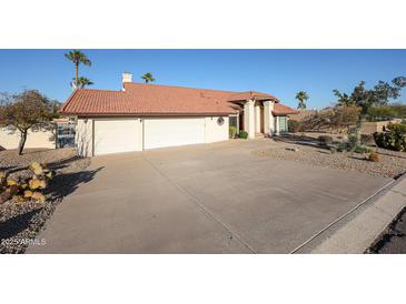 Charming single-story home featuring a three-car garage, desert landscaping, and a red tile roof at 17104 E Rand Dr, Fountain Hills, AZ 85268