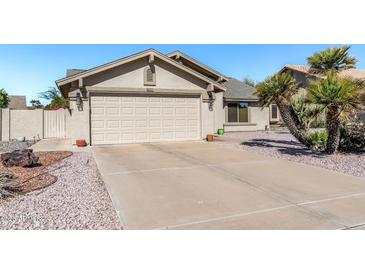 Tan home featuring a two car garage, desert landscaping and a driveway at 19930 N 98Th Ave, Peoria, AZ 85382