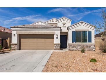 Charming single-story home with stone accents, two-car garage, and low-maintenance desert landscaping at 30940 W Indianola Ave, Buckeye, AZ 85396