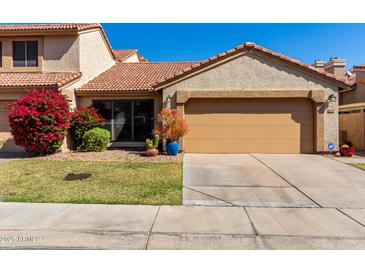 Charming single-Gathering home featuring a two-car garage, beautiful landscaping, and a classic desert tile roof at 4226 E Jojoba Rd, Phoenix, AZ 85044