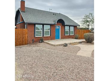 Charming brick home featuring a bright blue front door and low-maintenance desert landscaping at 1953 W Granada Rd, Phoenix, AZ 85009