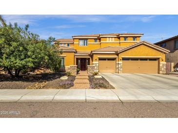 Stunning two-story home featuring a three car garage and lush front yard landscaping at 5032 W Yearling Rd, Phoenix, AZ 85083