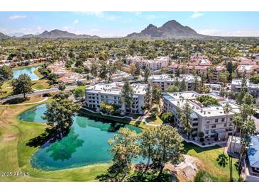 Aerial view of a lakeside apartment complex with lush landscaping, mature trees, and mountain views in the distance at 5124 N 31St Pl # 536, Phoenix, AZ 85016