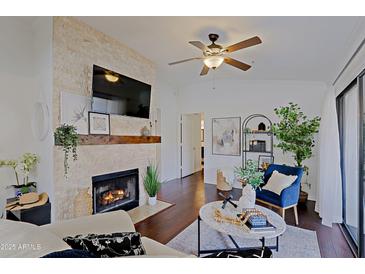 Bright living room with a stone fireplace, ceiling fan, and hardwood floors, creating an inviting atmosphere at 9990 N Scottsdale Rd # 2020, Paradise Valley, AZ 85253