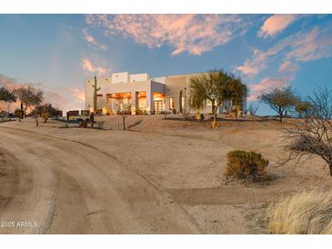 Desert residence showcasing a well-maintained landscape and a welcoming covered entrance, nestled into the beautiful desert terrain at 13502 E Jomax Rd, Scottsdale, AZ 85262