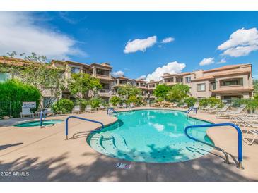 Resort-style pool with spa, surrounded by lush landscaping and multi-story condo buildings under sunny skies at 14000 N 94Th St # 1118, Scottsdale, AZ 85260