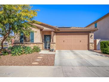 Charming single-story home featuring a desert landscape, a two-car garage, and a stone-accented facade at 14296 W Surrey Dr, Surprise, AZ 85379