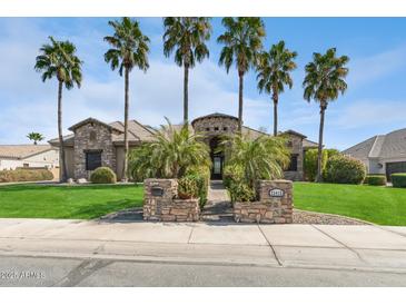 Elegant stone home with a circular entryway, palm trees, and a well-maintained front lawn at 23415 S 202Nd St, Queen Creek, AZ 85142