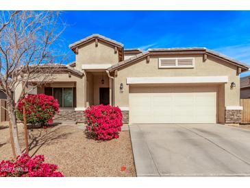 Inviting single-story home featuring a two-car garage and desert landscaping with bright pink bougainvillea bushes at 25907 N 134Th Dr, Peoria, AZ 85383