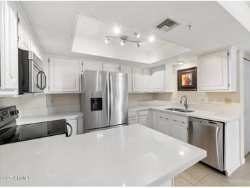 White kitchen features stainless steel appliances, ample countertop space, and natural light at 4200 N Miller Rd # 220, Scottsdale, AZ 85251