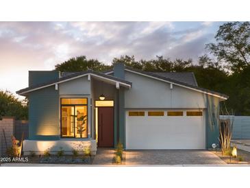 Beautiful single-story home with a red door, large window, and a white garage door and professional landscaping at 6710 N 9Th Dr, Phoenix, AZ 85013