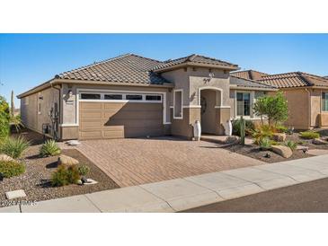 Charming single-story home featuring a well-manicured desert landscape, brick driveway, and tile roof at 18961 N 259Th Ave, Buckeye, AZ 85396